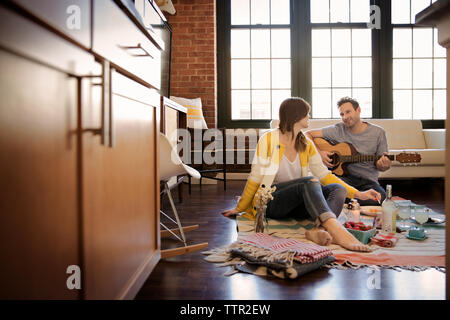 Man playing guitar for girlfriend at home Stock Photo