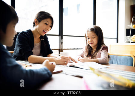 Happy mother teaching children at home on sunny day