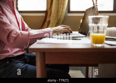 Side view of man using laptop at table Stock Photo