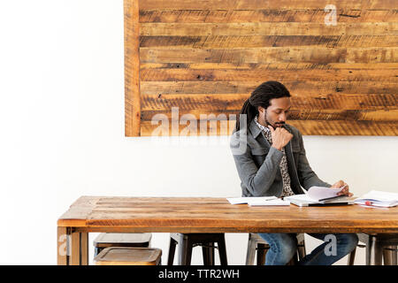 Young businessman analyzing documents while sitting in creative office Stock Photo