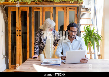 businessman using laptop while working with female colleague in office Stock Photo