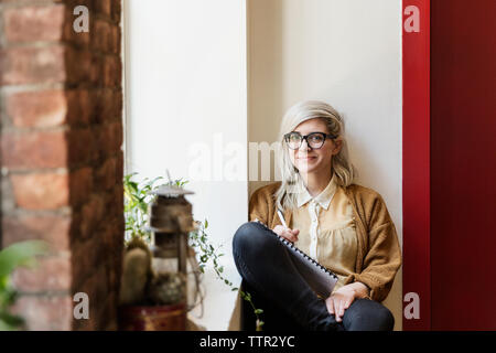 Portrait of confident young businesswoman sitting in creative office Stock Photo