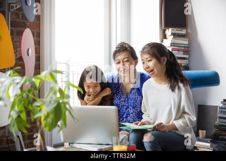 Cheerful mother and daughters doing video call with laptop at home Stock Photo