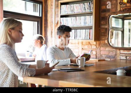 People resting while having coffee at bar counter in cafe Stock Photo
