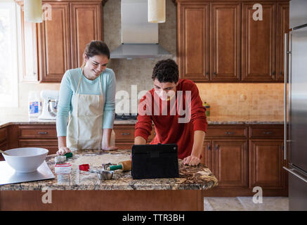 Happy siblings using laptop computer in kitchen at home Stock Photo