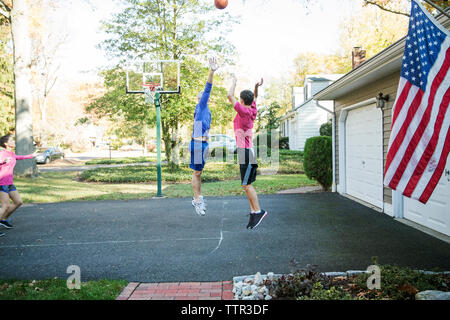 Senior man playing basketball with grandson at backyard Stock Photo