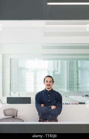 Businessman with arms crossed seen through glass window Stock Photo - Alamy