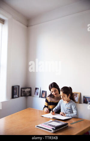Mother looking at girl studying Stock Photo