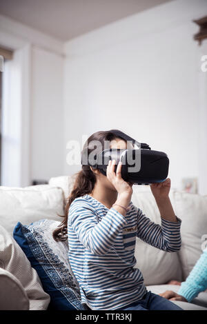 Girl using virtual reality simulator while sitting with sister at home Stock Photo