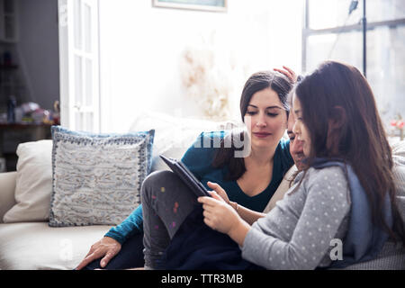 Girl with father and mother using tablet computer while sitting at home Stock Photo
