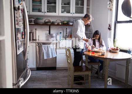 Father and daughter applying peanut butter on bread Stock Photo
