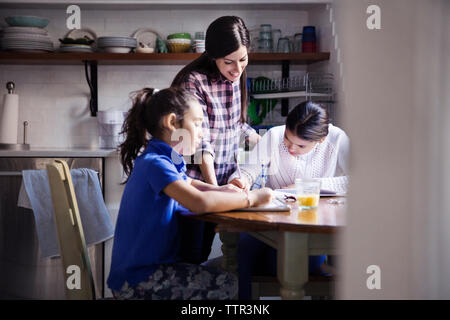 Woman looking at daughters studying seen through doorway Stock Photo
