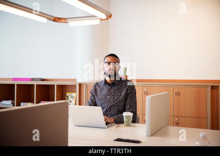 Portrait of businessman using laptop computer at table in office Stock Photo