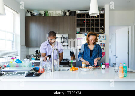 Woman making breakfast while man filling jug with water on kitchen island Stock Photo