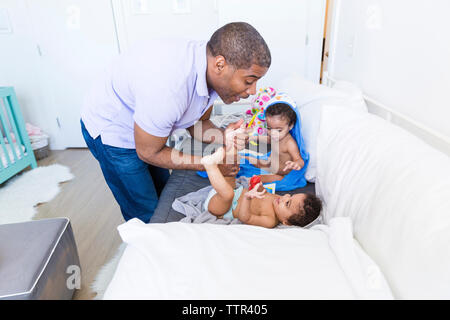 Father playing with daughter lying beside sister on sofa Stock Photo