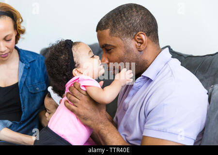 Baby girl playing with father with mother and sister sitting in background Stock Photo