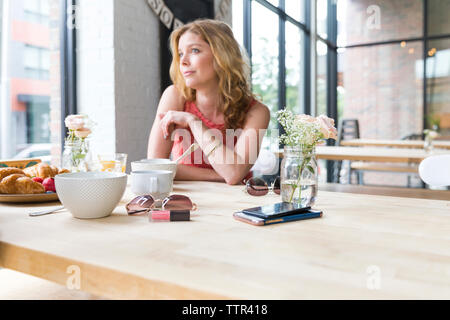Thoughtful woman looking away while sitting in cafe Stock Photo