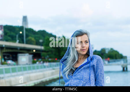 Thoughtful woman wearing hooded jacket while looking away Stock Photo