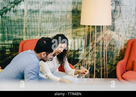 High angle view of colleagues discussing photograph printout while sitting in creative office Stock Photo