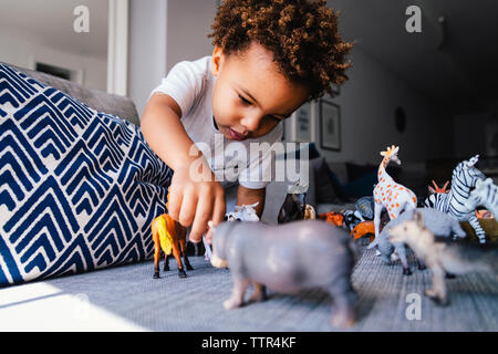 Low angle view of cute boy playing with toys on sofa at home Stock Photo