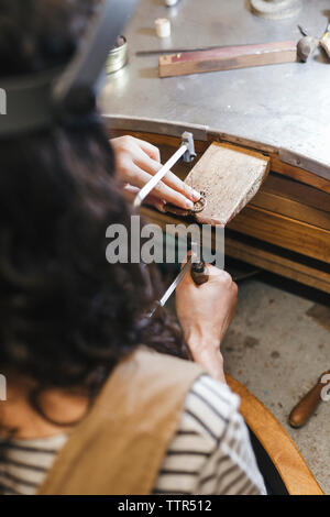 Cropped hands of female teacher teaching student to make ring on table in workshop Stock Photo