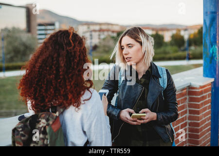 Two young student using smartphone at the park together Stock Photo