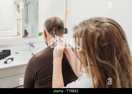 Young girl using hair clippers to cut her fathers hair at home Stock Photo