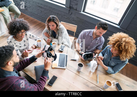 High angle view of business people examining virtual reality simulator in office Stock Photo