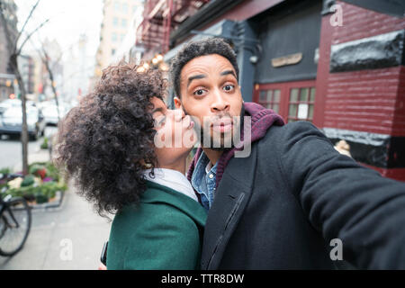 Woman kissing man while standing in city Stock Photo