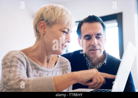Senior woman showing laptop computer to man at home Stock Photo