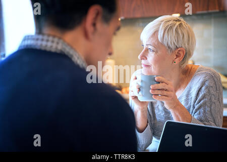Thoughtful senior woman looking away while sitting by man at home Stock Photo