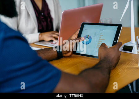 Midsection of businessman using tablet computer while sitting at desk in office Stock Photo