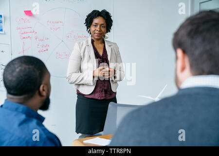 businesswoman discussing with male colleagues during meeting in office Stock Photo