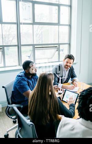 High angle view of business people discussing over wind turbine models in meeting Stock Photo