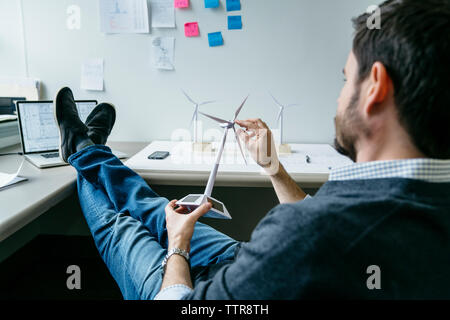 businessman spinning windmill model while sitting in office Stock Photo