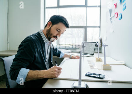 businessman working on wind turbine models in office Stock Photo