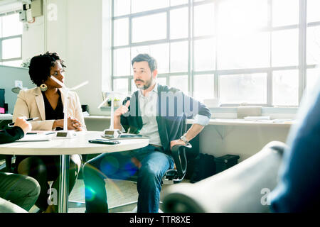 business people discussing over windmill models while sitting at desk in office Stock Photo