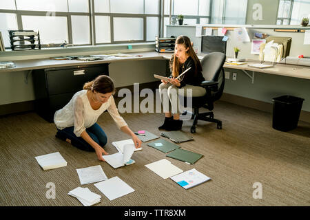 businesswomen arranging documents on floor in office Stock Photo