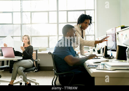 businesswoman explaining to colleague using desktop computer Stock Photo