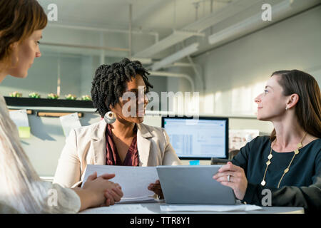 businesswomen discussing over tablet computer while sitting in office Stock Photo