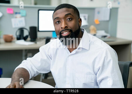 Portrait of confident businessman sitting at table in office Stock Photo