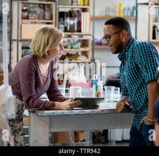 business people discussing over tablet computer while leaning on table in office Stock Photo