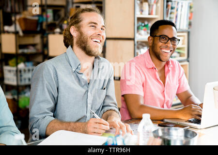 Happy businessmen looking away while sitting at conference table Stock Photo