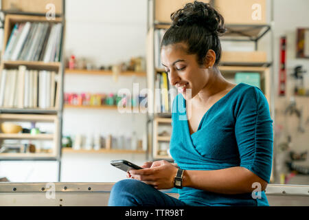 Happy businesswoman using smart phone while sitting in office Stock Photo