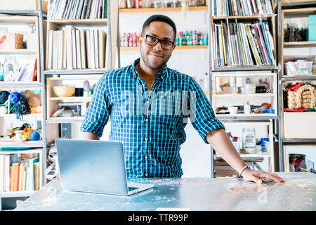 Portrait of confident businessman standing against racks while working in office Stock Photo