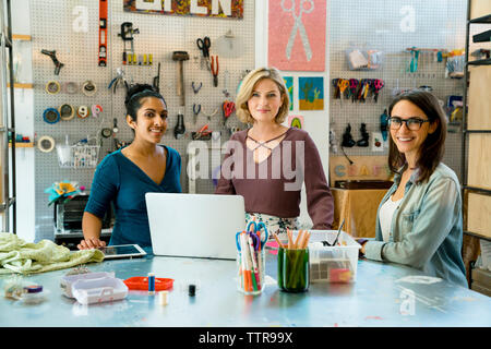 Portrait of confident businesswomen standing by work bench Stock Photo