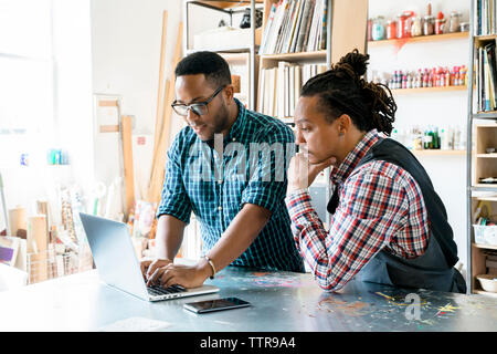 businessmen working on laptop computer while standing by table Stock Photo