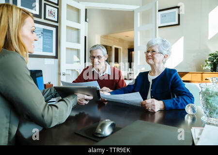 Senior couple holding documents while discussing with financial advisor in office Stock Photo