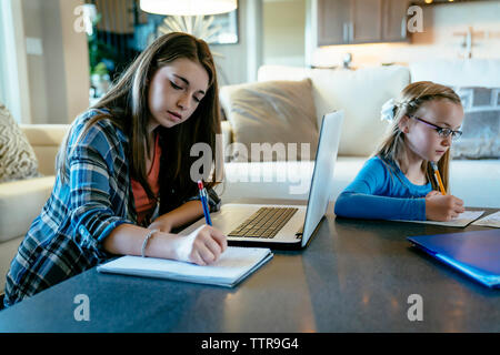 Sisters doing homework at table Stock Photo