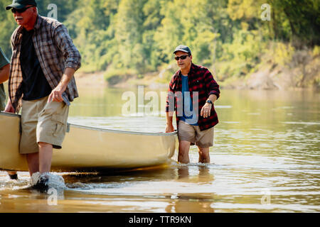 Male friends pushing boat in lake Stock Photo